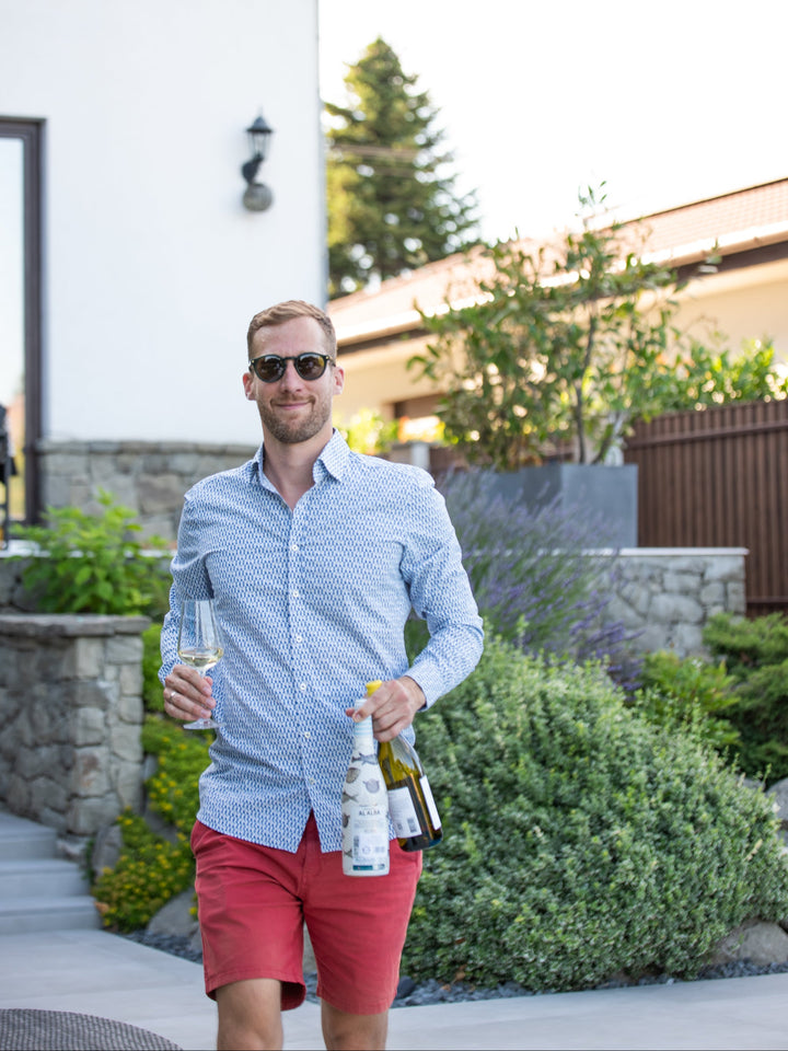 Man holding wine bottles in a backyard setting
